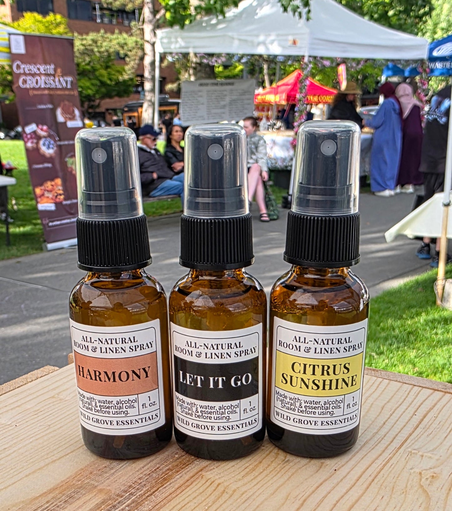 Three small bottles with labels on a wooden surface outdoors.