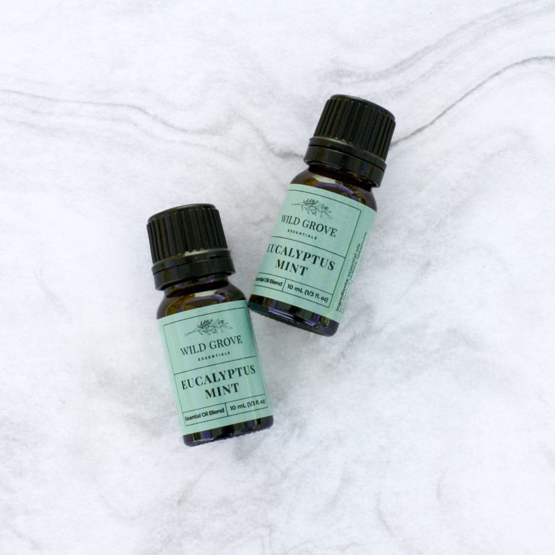 10ml essential oil amber bottles in Eucalyptus Mint scent with a blue label on a marble background.