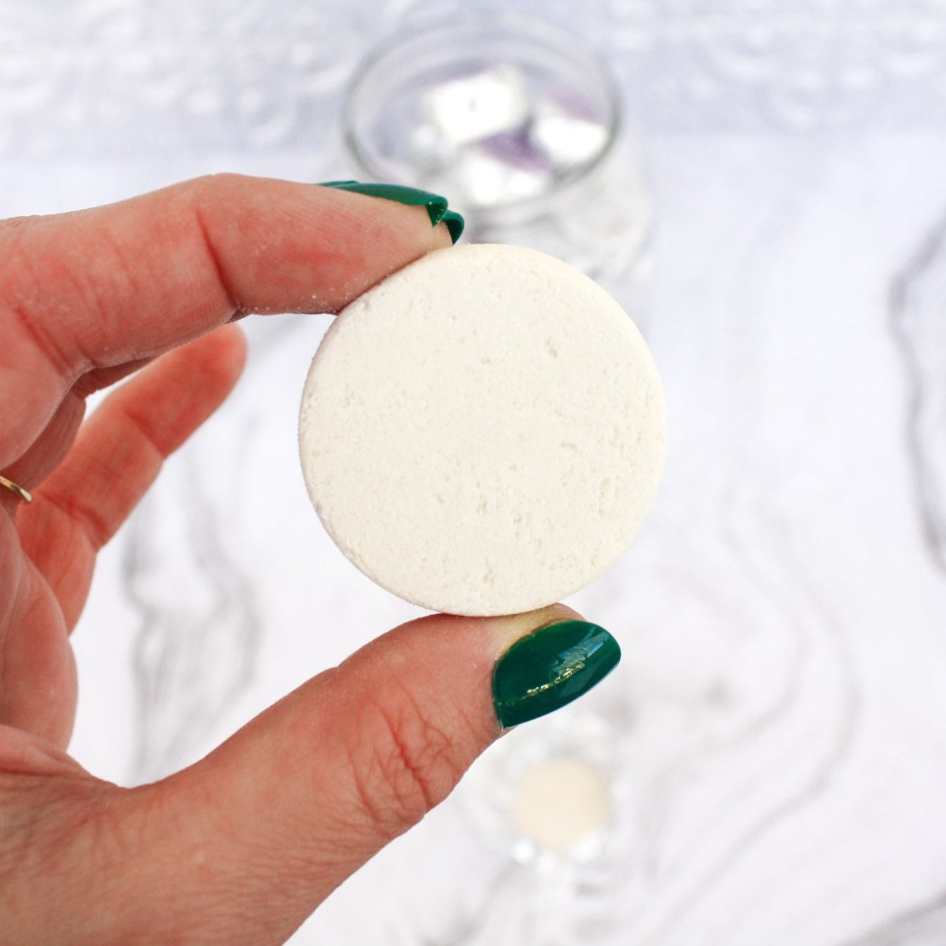 Close up image of an unwrapped bath and shower fizzy, a small white puck.