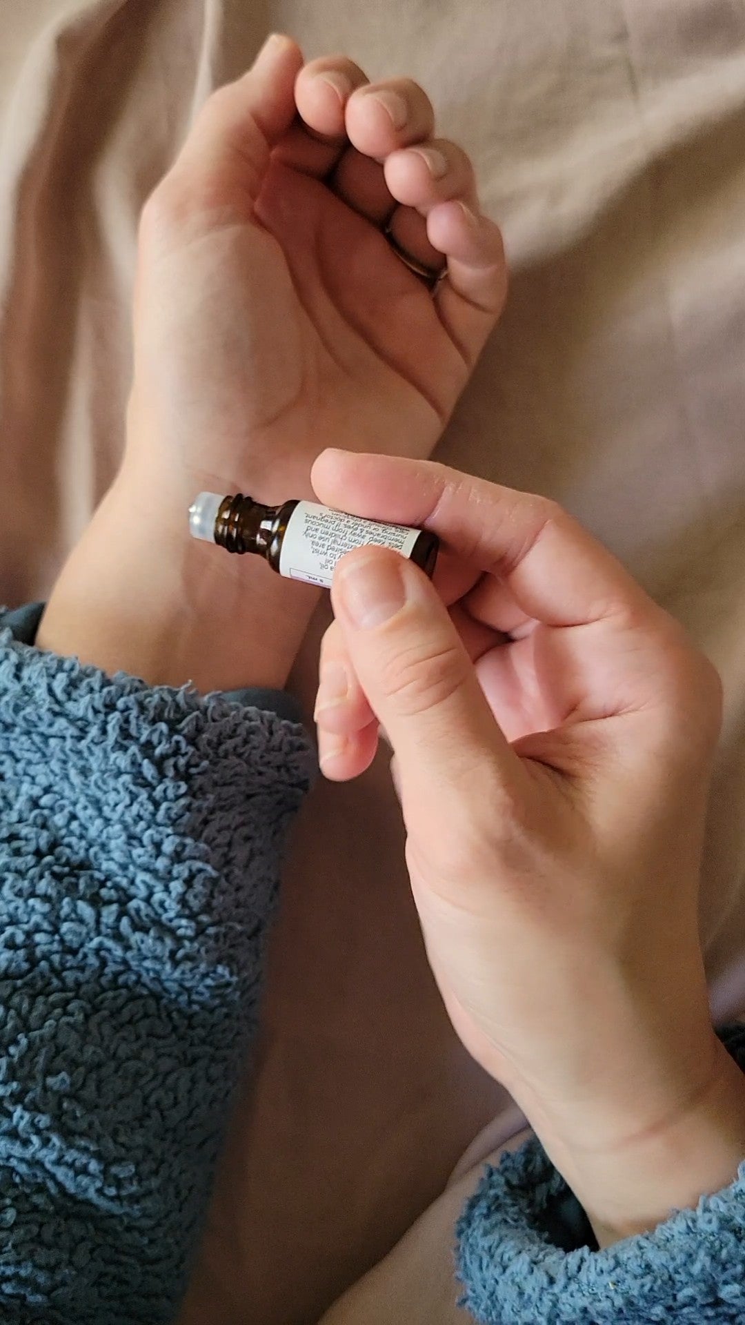 Mini essential oil roll on in 5ml bottle being used to apply essential oil to wrist.