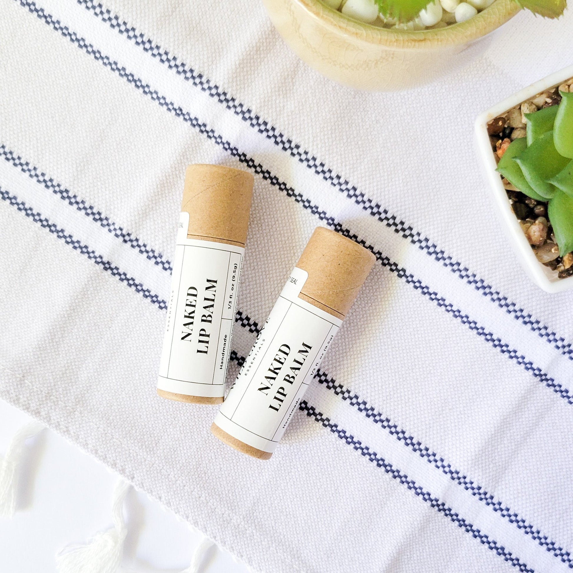 Naked lip balm in cardboard tubes on a hand towel background with white labels.