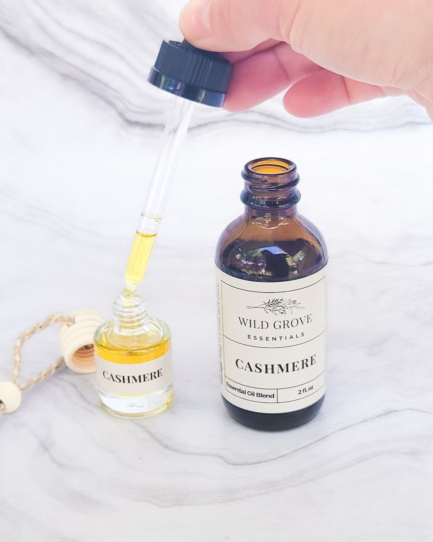 2oz essential oil dropper bottle being used to refill a glass bottle car freshener. Both in Cashmere scent.