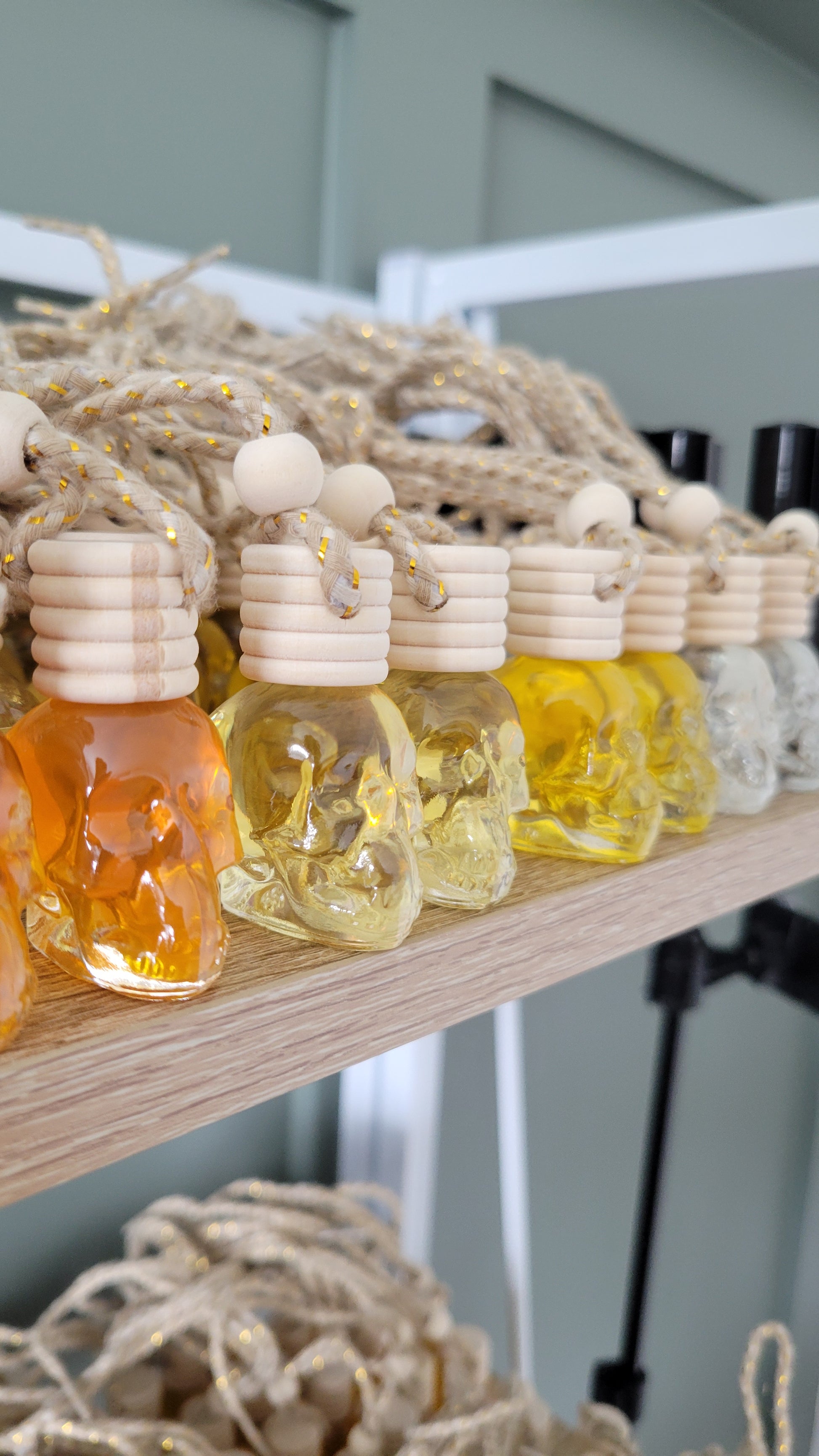 Car fresheners in skull shaped glass bottles with wood top lined up on a shelf.